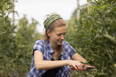 Young woman working as vegetable grower or farmer in the field