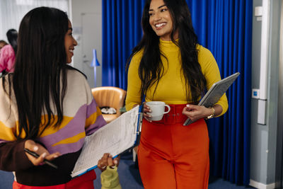 Smiling female business professionals discussing together at office