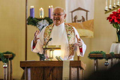 Smiling priest giving speech in church