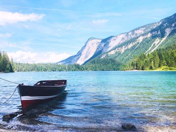 Boat moored on lake against sky