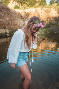 Beautiful young ginger fashion model boho style woman standing in lake in nature 