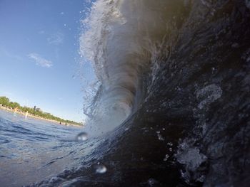 Sea waves splashing on shore against sky