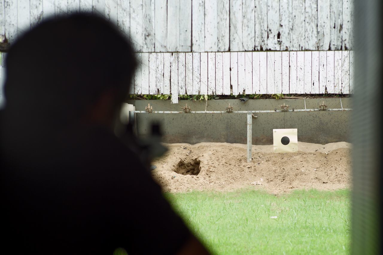 REAR VIEW OF MAN PHOTOGRAPHING CAMERA ON GRASS