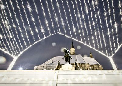 Low angle view of statue against illuminated building