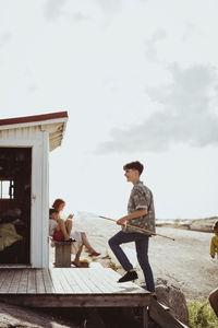 Teenage boy looking away while mother sitting with son on seat by cabin