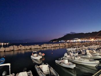 Boats moored at harbor against clear blue sky