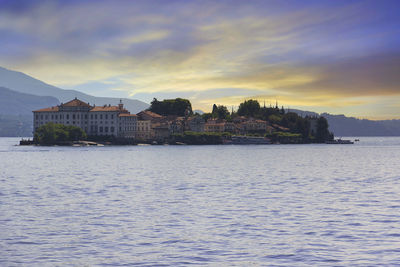 Houses by sea against sky during sunset