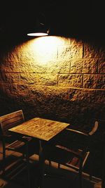 Empty chairs and table against wall at restaurant