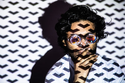 Young man wearing sunglasses against wall with shadow