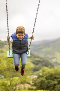 Portrait of boy swinging in playground