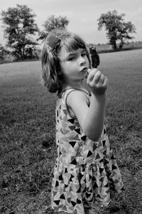 Girl holding wood while standing on field