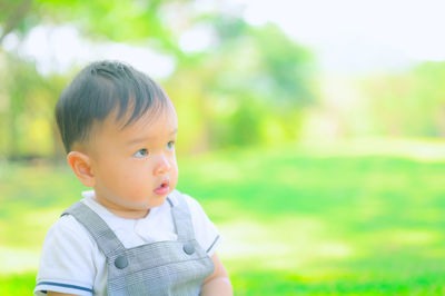 Portrait of cute boy looking away on field