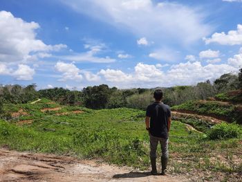 Rear view of man standing on landscape against sky