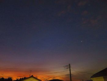 Low angle view of silhouette electricity pylon against sky at night