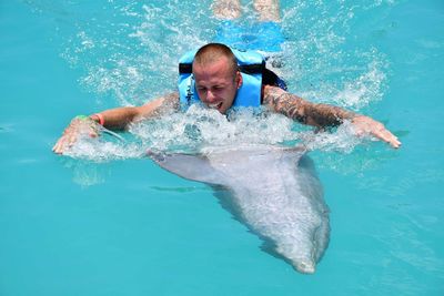 Man swimming with dolphin in sea