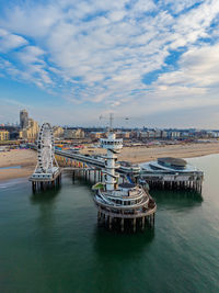 Aerial view of coastal pier with spiral observation tower, ferris wheel, and dome structure framed