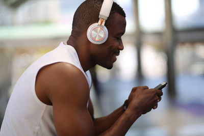 Smiling man using phone while wearing headphones