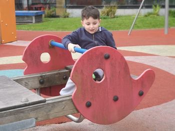 Cute boy playing on outdoor play equipment at playground