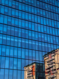 Low angle view of glass building against blue sky