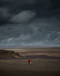 People walking on landscape against sky