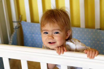 Happy one year old girl with blue eyes and blond after waking up in the morning in her bed.