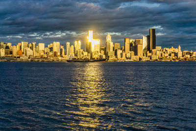 The setting sun makes a section of the city of seattle shine across elliott bay.