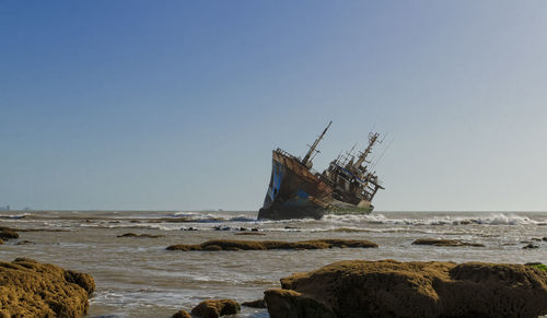 Abandoned boat on beach against clear sky