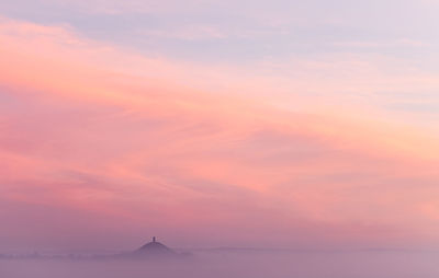 Scenic view of glastonbury tor against sky during misty sunrise