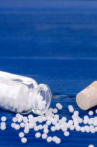 Close-up of pill and glass bottle on blue table