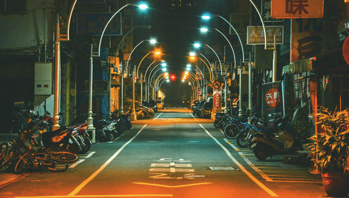 Empty road in illuminated lights at night