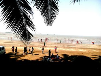 People playing on beach against clear sky