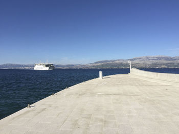 Pier over sea against clear blue sky