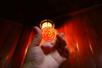 Cropped hand holding soap against illuminated light