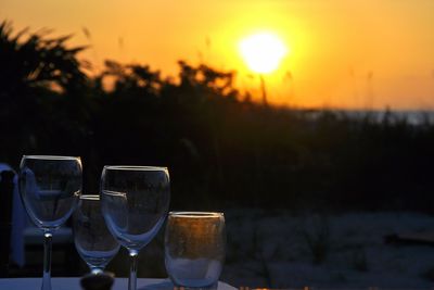 Wine glasses on table against sky during sunset