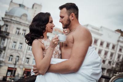 Couple holding coffee cup looking at cityscape