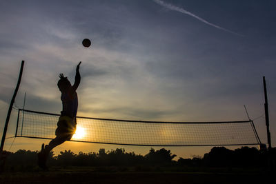 Silhouette man playing volleyball against sky during sunset