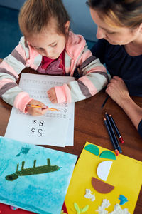 Little girl preschooler learning to write letters with help of her mother. kid writing letters