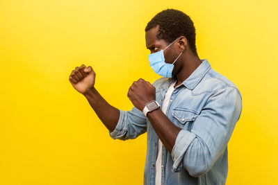 Full length of man standing against yellow background