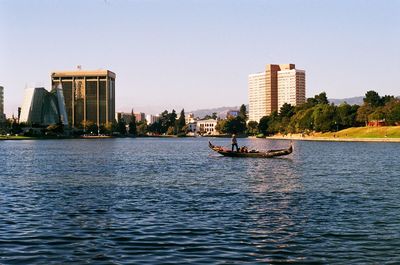 Man sailing boat in lake against clear sky