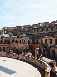 Low angle view of old amphitheater against cloudy sky at el djem