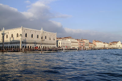 Doge palace by grand canal against cloudy sky