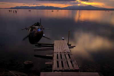 Pier over lake against sky during sunset