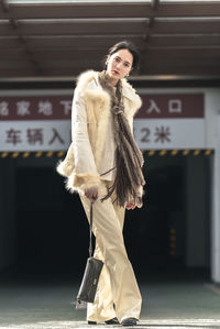 Portrait of young woman standing against wall