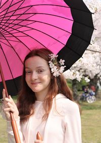 Portrait of smiling woman holding pink flowering plants