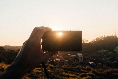 Close-up of hand holding sun against clear sky during sunset