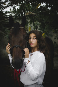 Portrait of young woman riding horse in park