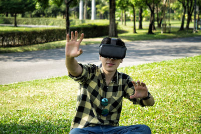 High angle view of man wearing virtual reality while sitting on field