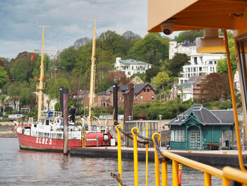 Sailboats moored on river by buildings in city against sky