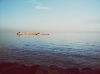 Barge amidst sea against sky