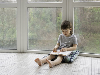 Full length of boy sitting on window